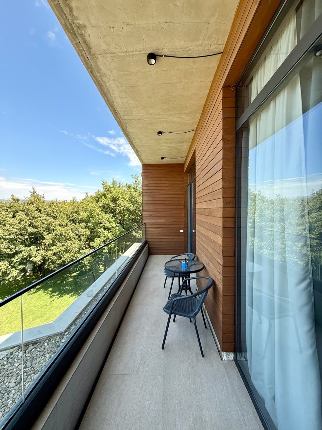 A balcony on the upper floor, facing the tree line.