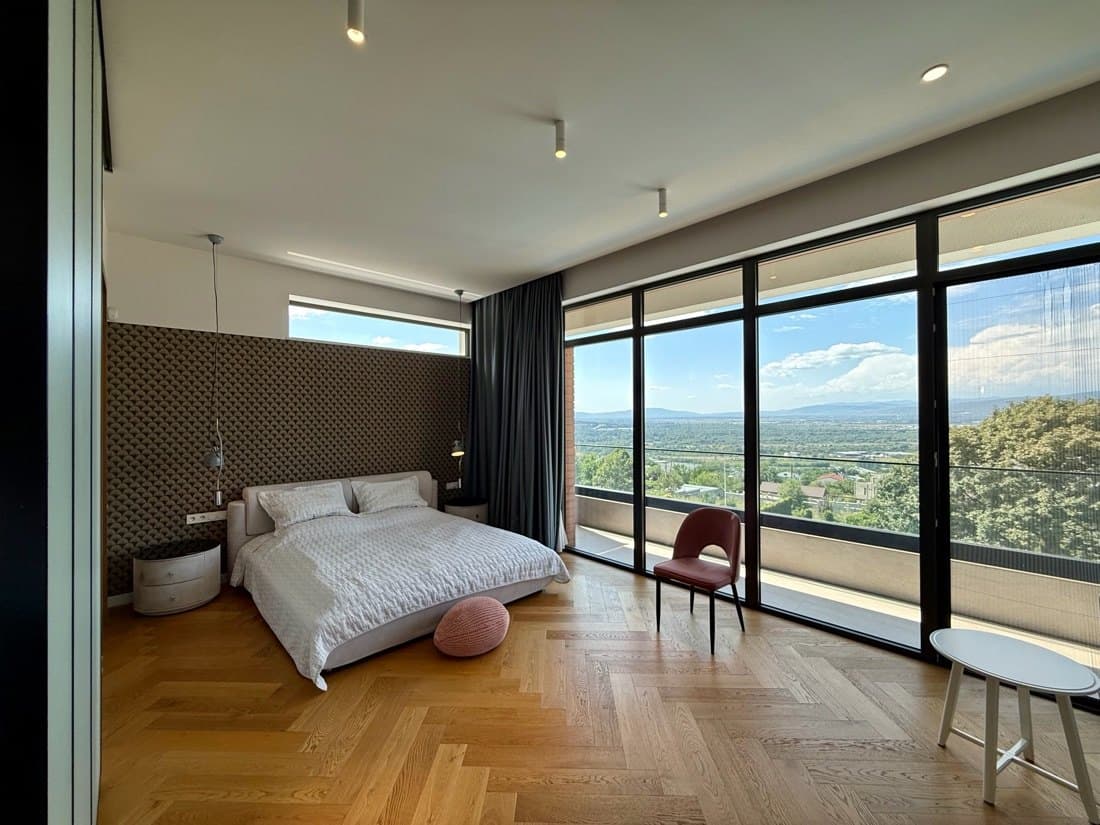 The upper floor: a bedroom glazed to the tree line.