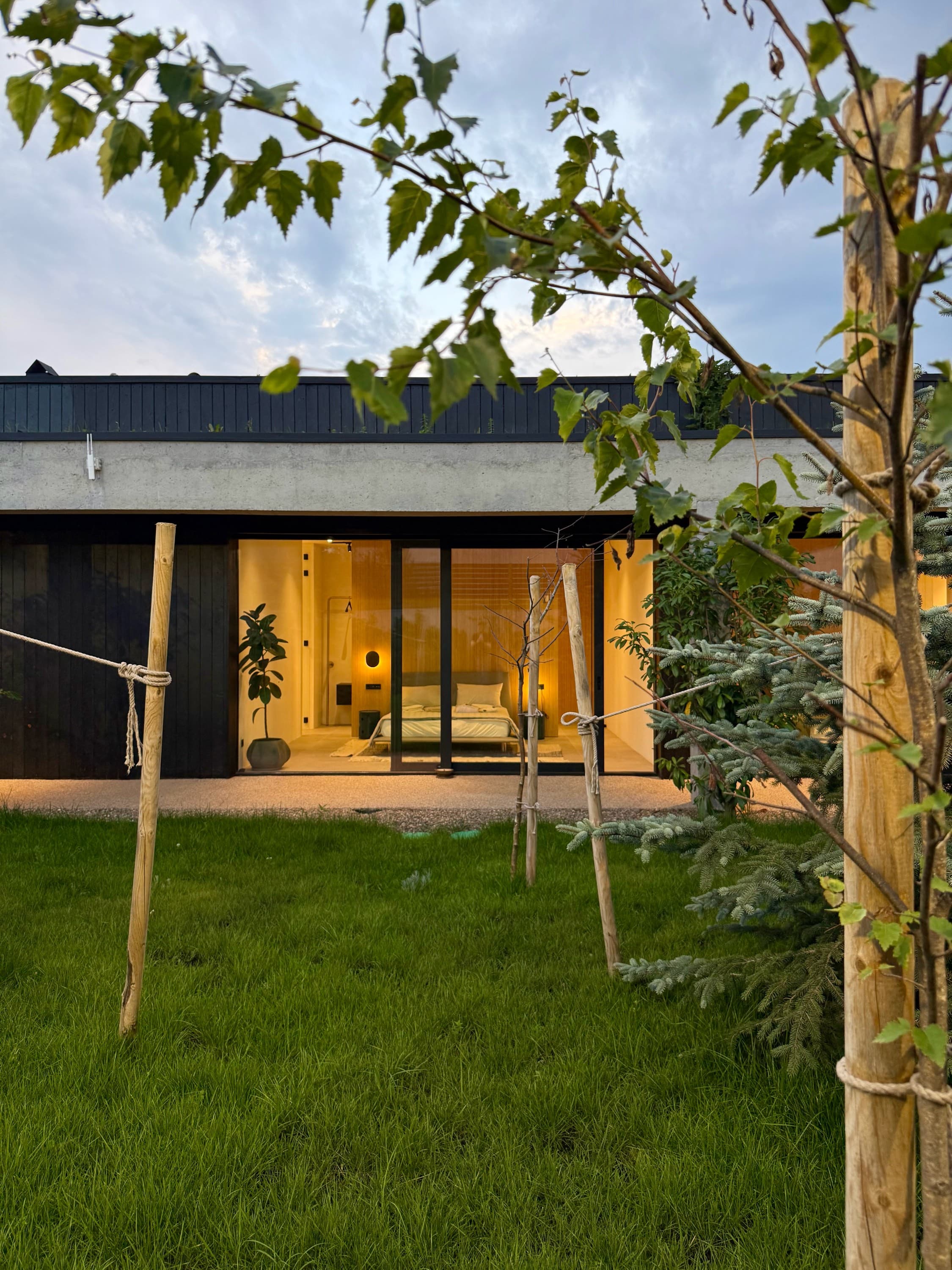 The glazed elevation at dusk, lit from within, seen across the lawn.
