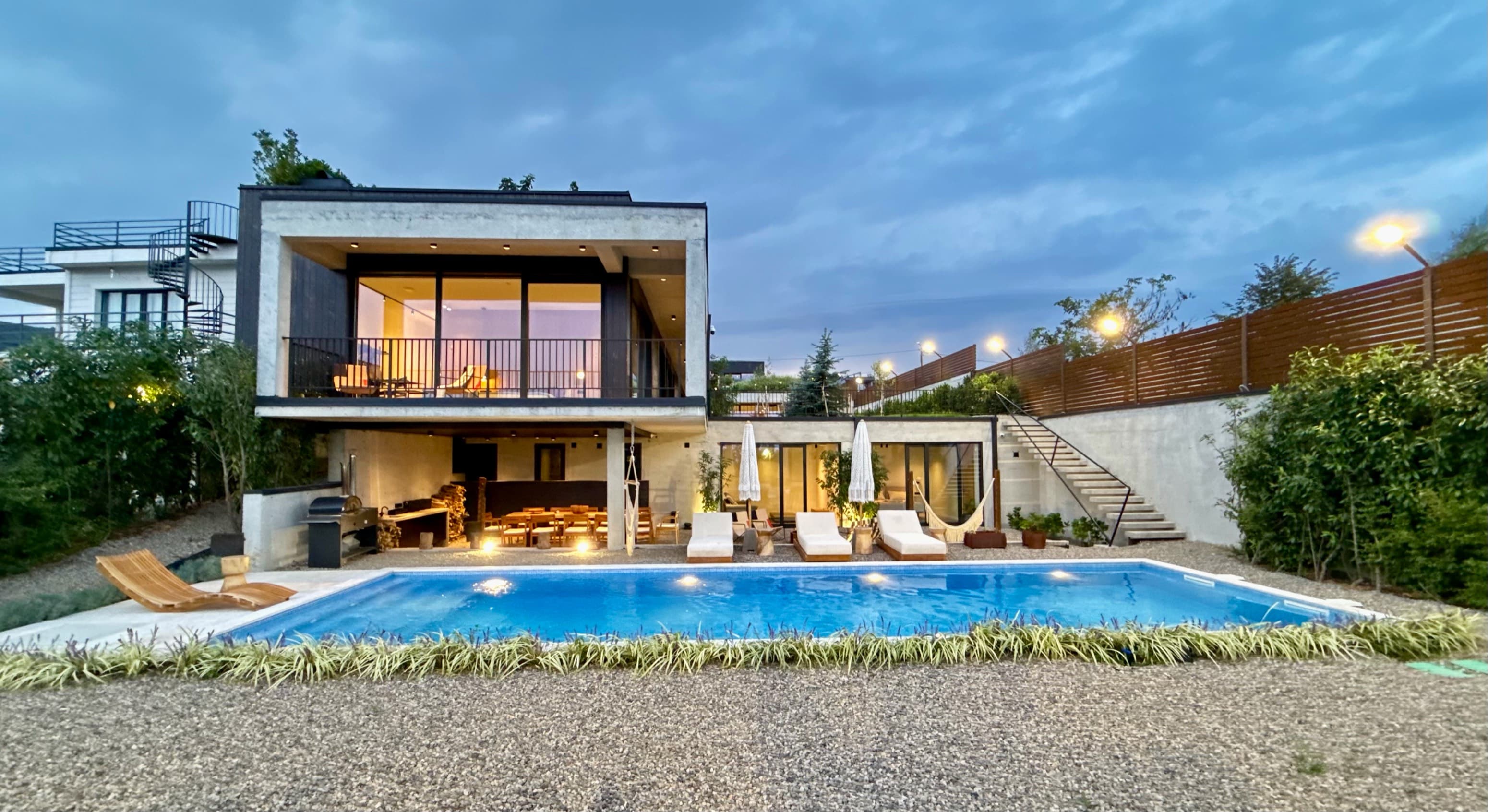 The villa and its pool at dusk, lit from within